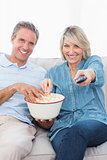 Couple watching tv and eating popcorn on the sofa