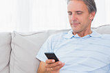 Man relaxing on his couch sending a text