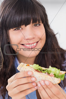 Cheerful brunette having a salad sandwich