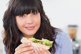 Happy brunette having a salad sandwich