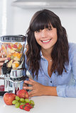 Smiling brunette with juicer full of fruit