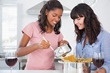 Cheerful friends preparing spaghetti dinner together