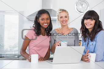 Pretty friends having coffee together with laptop