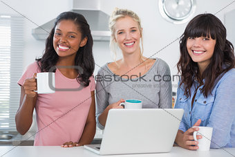 Happy friends having coffee together with laptop
