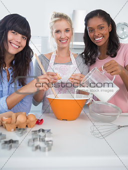 Happy friends making pastry together looking at camera