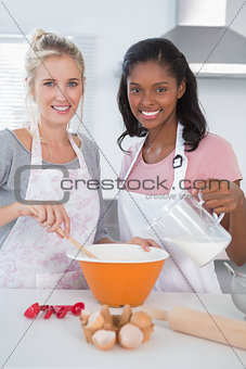 Smiling friends making dough together looking at camera