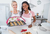 Cheerful woman showing freshly baked cookies with friend