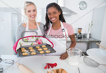 Cheerful woman showing freshly baked cookies with friend