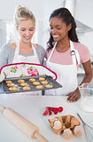 Smiling woman showing freshly baked cookies to friend