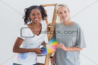 Friendly housemates choosing colour for wall looking at camera