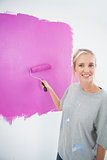 Happy blonde painting her wall pink