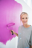 Pretty woman painting her wall pink