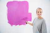 Happy young woman painting her wall pink