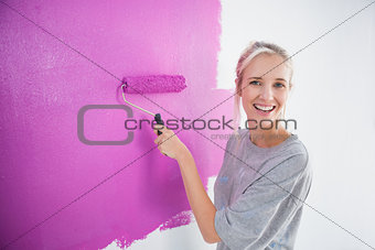 Laughing woman painting her wall in pink