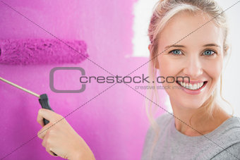 Smiling woman painting her wall in pink