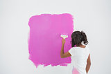 Young woman painting her wall in pink