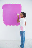 Happy woman painting her wall in bright pink