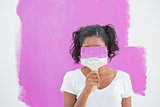 Happy woman hiding her face with paintbrush