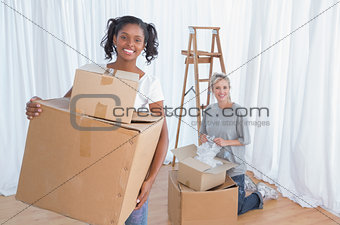 Young friends unpacking in their new home and smiling at camera