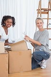 Cheerful friends unpacking boxes in new home