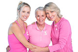 Embracing women wearing pink tops and ribbons for breast cancer