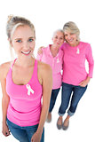 Three women wearing pink tops and breast cancer ribbons