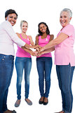 Happy women wearing breast cancer ribbons putting hands together smiling at camera
