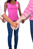 Women wearing pink and ribbons for breast cancer holding hands