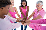Women wearing pink and ribbons for breast cancer putting hands together