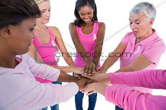 Women wearing pink and ribbons for breast cancer putting hands together
