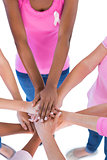 Group wearing pink and ribbons for breast cancer putting hands together