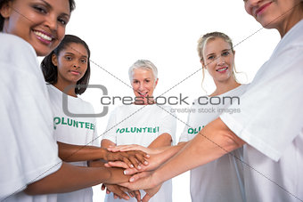 Team of female volunteers with hands together smiling at camera