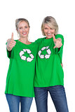 Two happy women wearing green recycling tshirts giving thumbs up