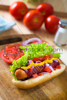 hot dog and bacon served with mustard tomatoes and plenty of bac