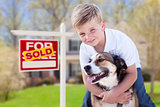 Young Boy and His Dog in Front of Sold For Sale Sign and House