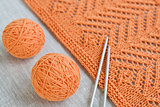 Orange balls, knitted pattern and knitting needles