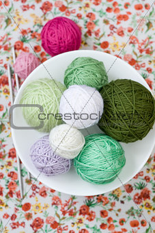 A lot of bright balls of knitting on the background of a red flower