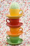 Four colorful cups and balls of yarn on a background of a red flower