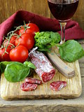Still life of delicacy salami, tomatoes and basil -  rustic style