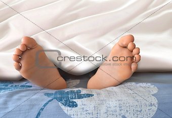 Feet under blanket in bedroom