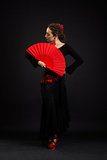 Young spanish woman dancing flamenco on black