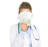 Doctor woman hiding behind fan of euros