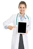 Smiling doctor woman pointing on tablet pc