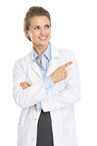 Smiling doctor woman pointing on copy space