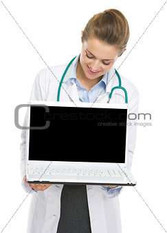 Happy doctor woman looking in laptop blank screen