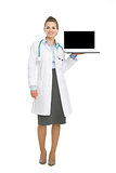 Full length portrait of happy doctor woman showing laptop blank 