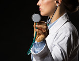 Closeup on doctor woman using stethoscope isolated on black