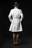 Full length portrait of doctor woman isolated on black. rear vie