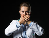 Portrait of doctor woman showing speak no evil gesture isolated 