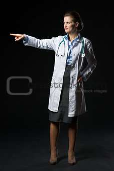 Full length portrait of doctor woman pointing on copy space isol